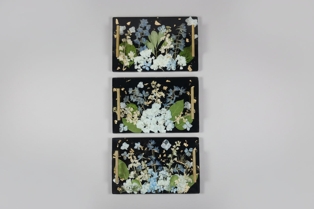 Three decorative panels with floral designs on a black background, arranged vertically on a gray surface.