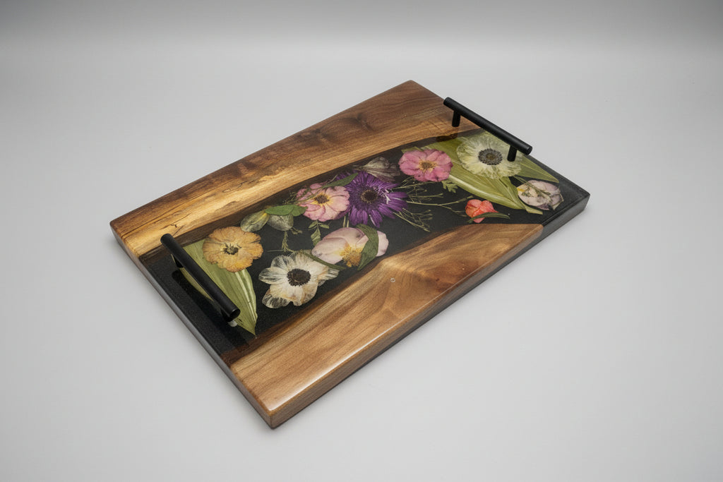 walnut wood charcuterie board with flower preserved inside with black background