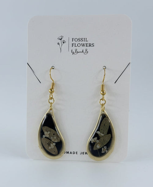 Teardrop-shaped earrings on a Fossil branded card with a wooden surface background