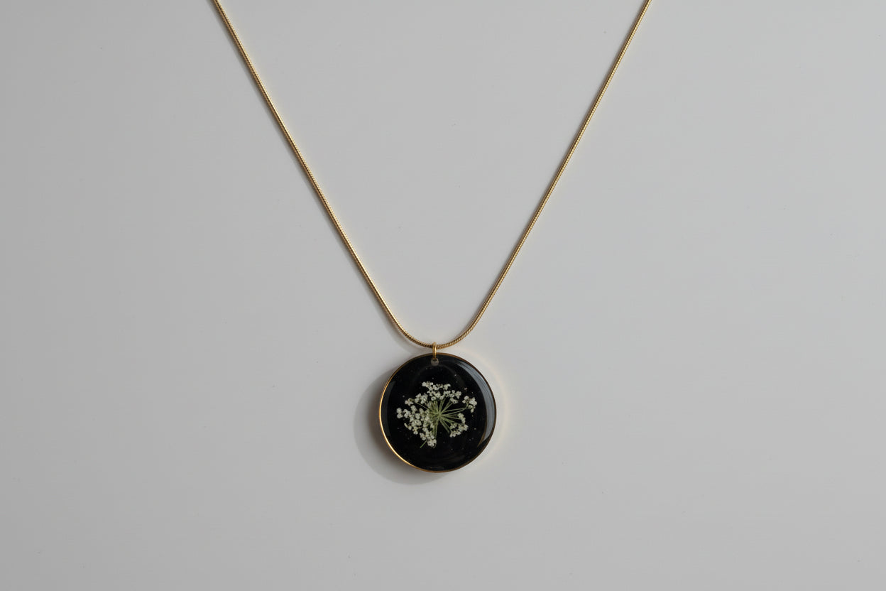 Necklace with a round pendant featuring a pressed flower on a dark background