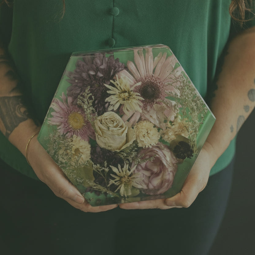 Person holding a hexagonal box with floral design against a dark background