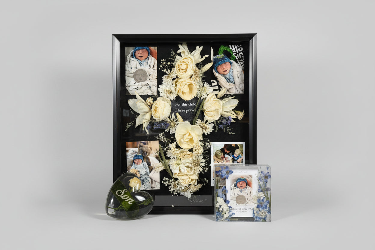 Decorative shadow box with flowers and baby photos on a pink surface