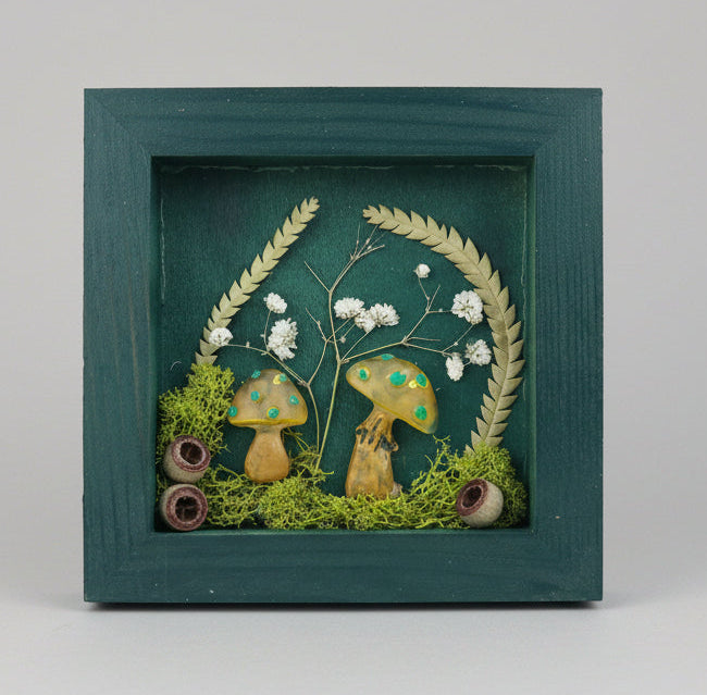 Decorative shadow box with mushrooms and plants on a light blue background