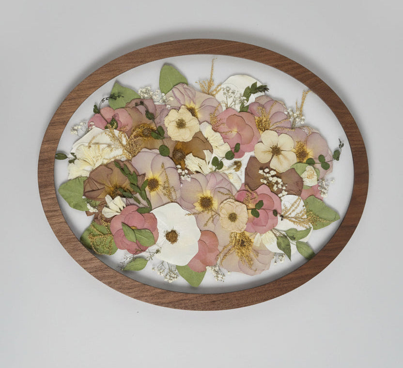 Round wooden frame with pressed flowers on a white background