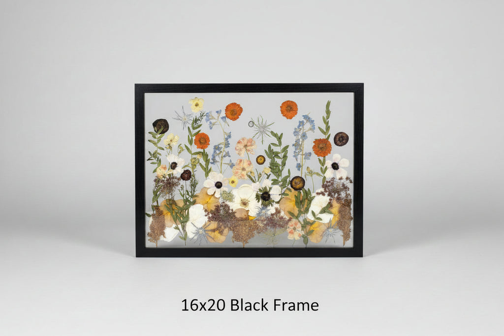 Framed artwork with pressed flowers and leaves on a wooden background