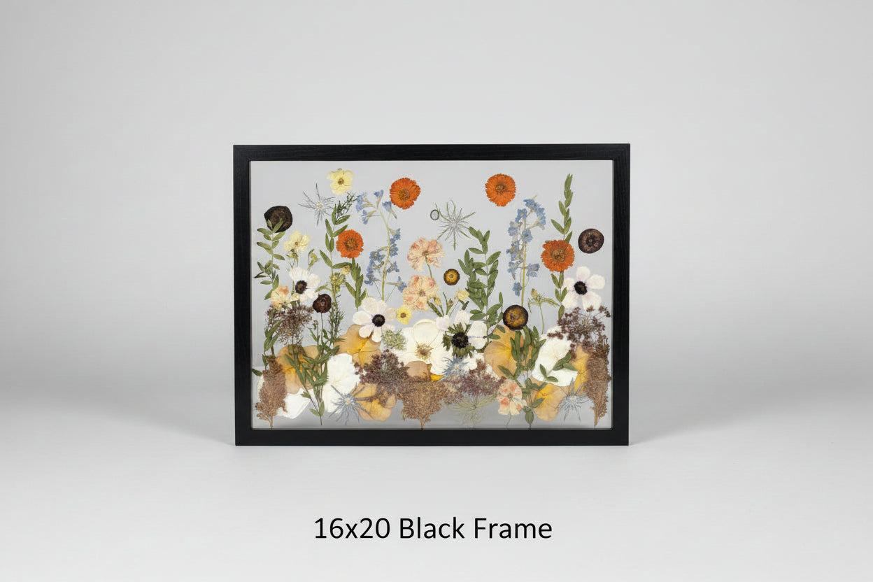 Framed artwork with pressed flowers and leaves on a wooden background