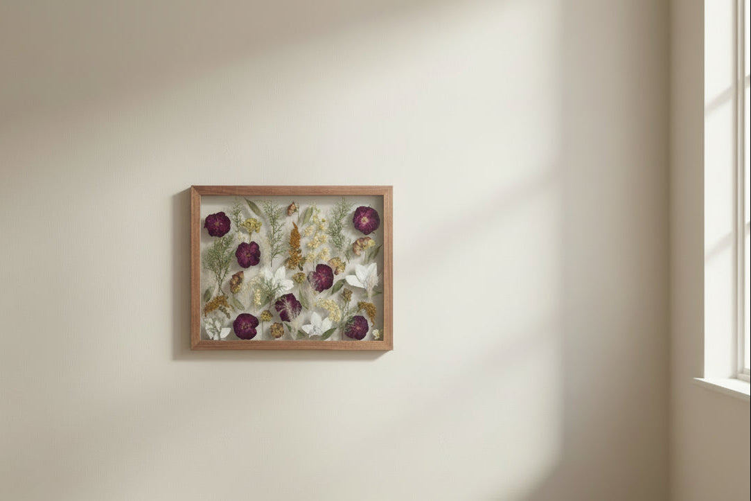 Pressed floral frame hanging on a beige wall near window
