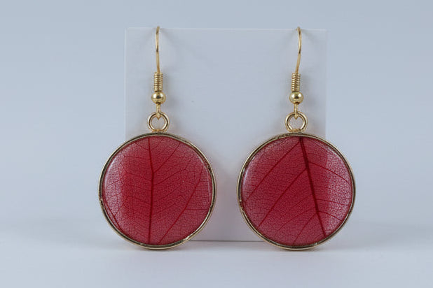 Red earrings with gold accents on a wooden surface
