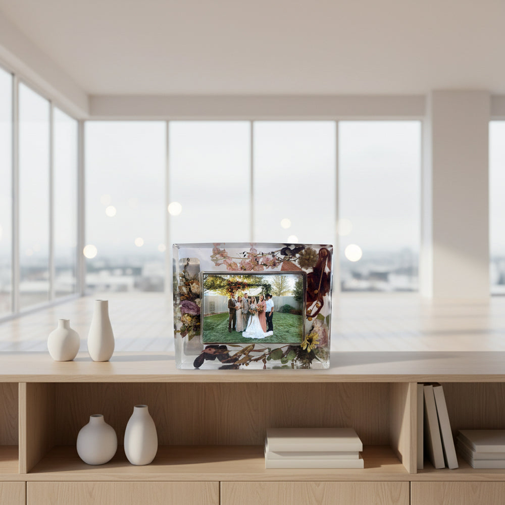 Decorative photo frame with floral design containing a wedding photo of a couple and guests.