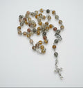 Rosary with multicolored beads and a cross on a marble surface