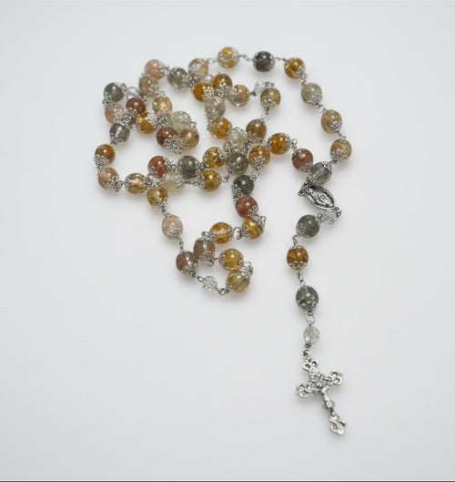 Rosary with multicolored beads and a cross on a marble surface