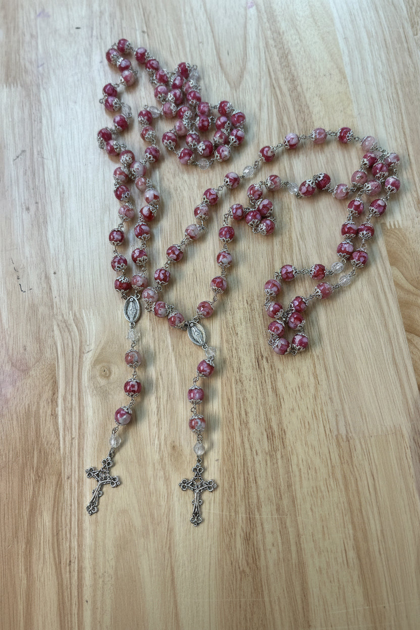 two pink rosaries laying on a light wood surface