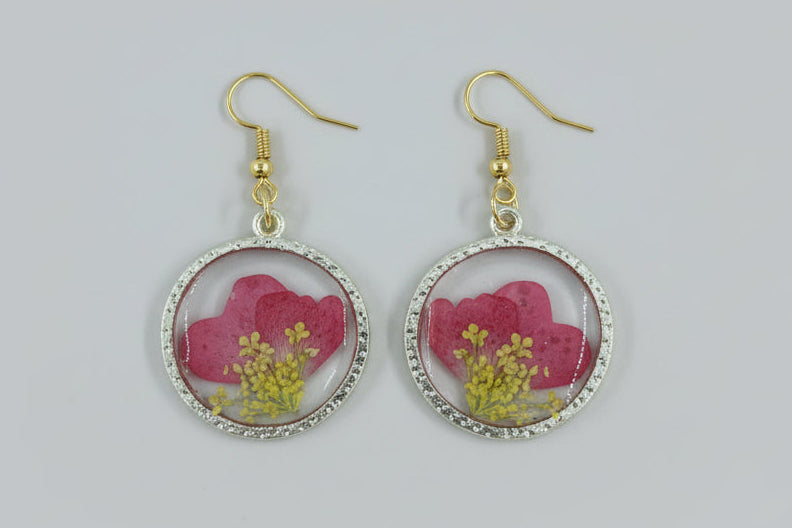 Pair of earrings with pink and yellow floral design on a gray background
