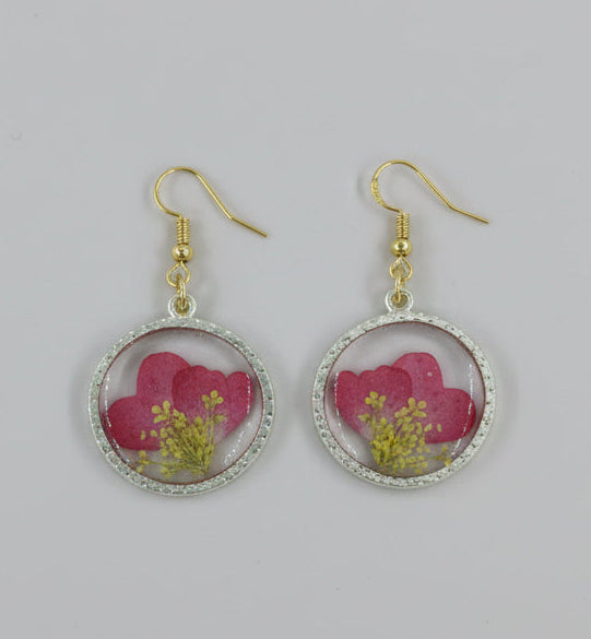 Pair of earrings with pink floral design on a gray background