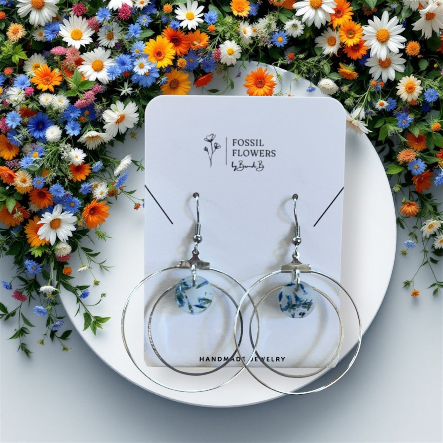 Earrings on a 'Fossil Flowers' branded card with colorful flowers in the background