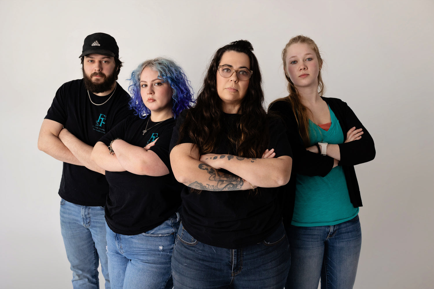 Four people standing together with arms crossed against a plain background