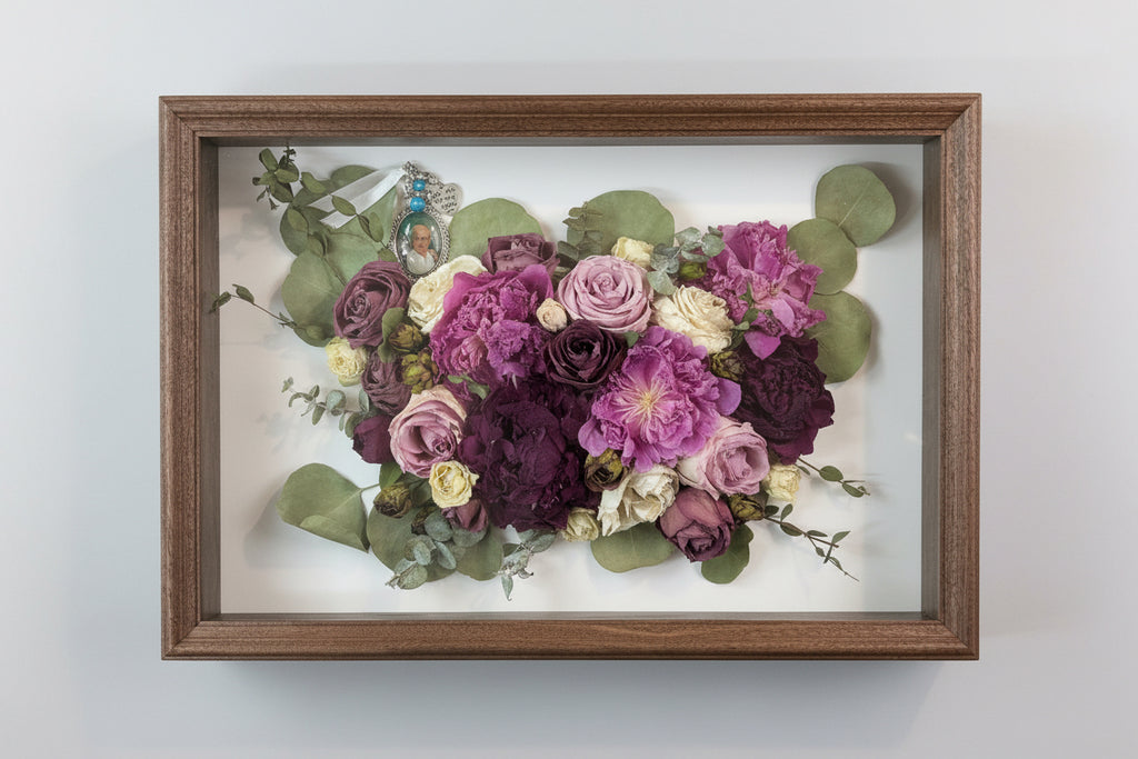 Framed bouquet of pressed flowers with a wooden frame on a white background