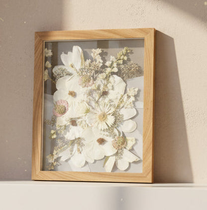 Framed floral artwork on a white ledge with a window in the background