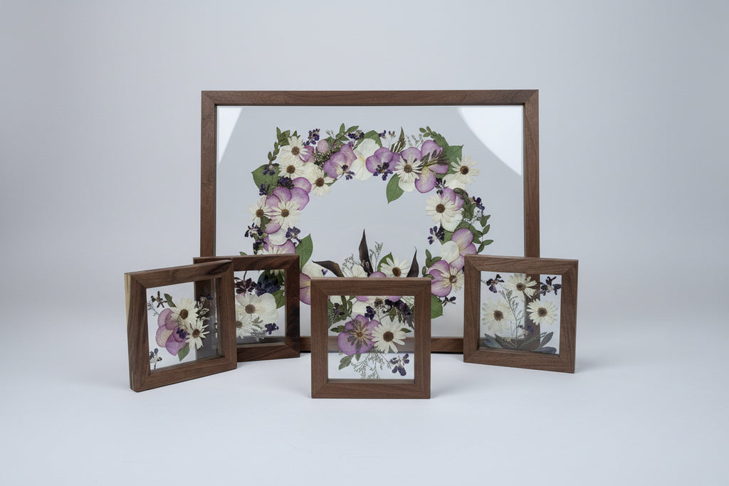 Decorative wreath with floral elements framed in a wooden box on a white wall.