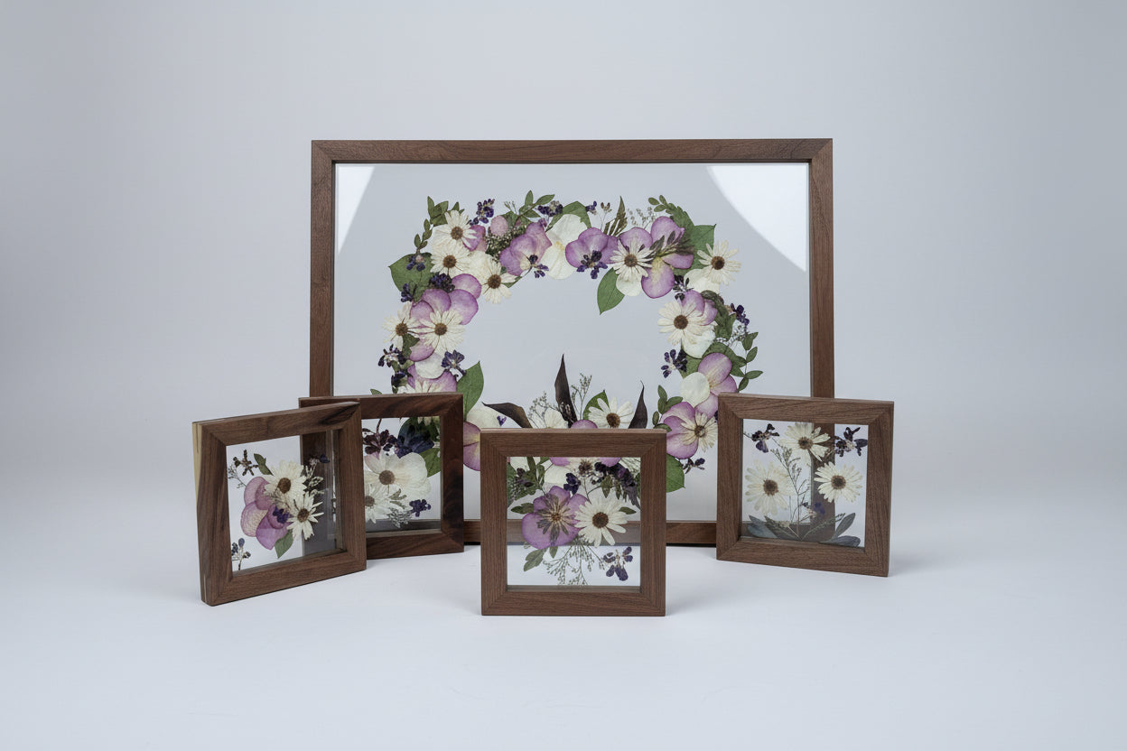 Decorative wreath with floral elements framed in a wooden box on a white wall.