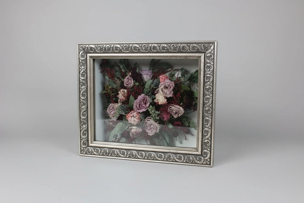 Framed artwork of a floral bouquet on a wooden surface