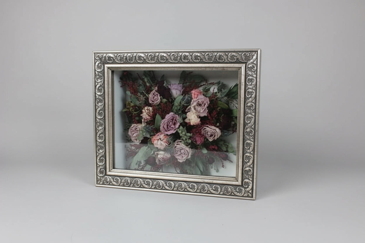 Framed artwork of a floral bouquet on a wooden surface