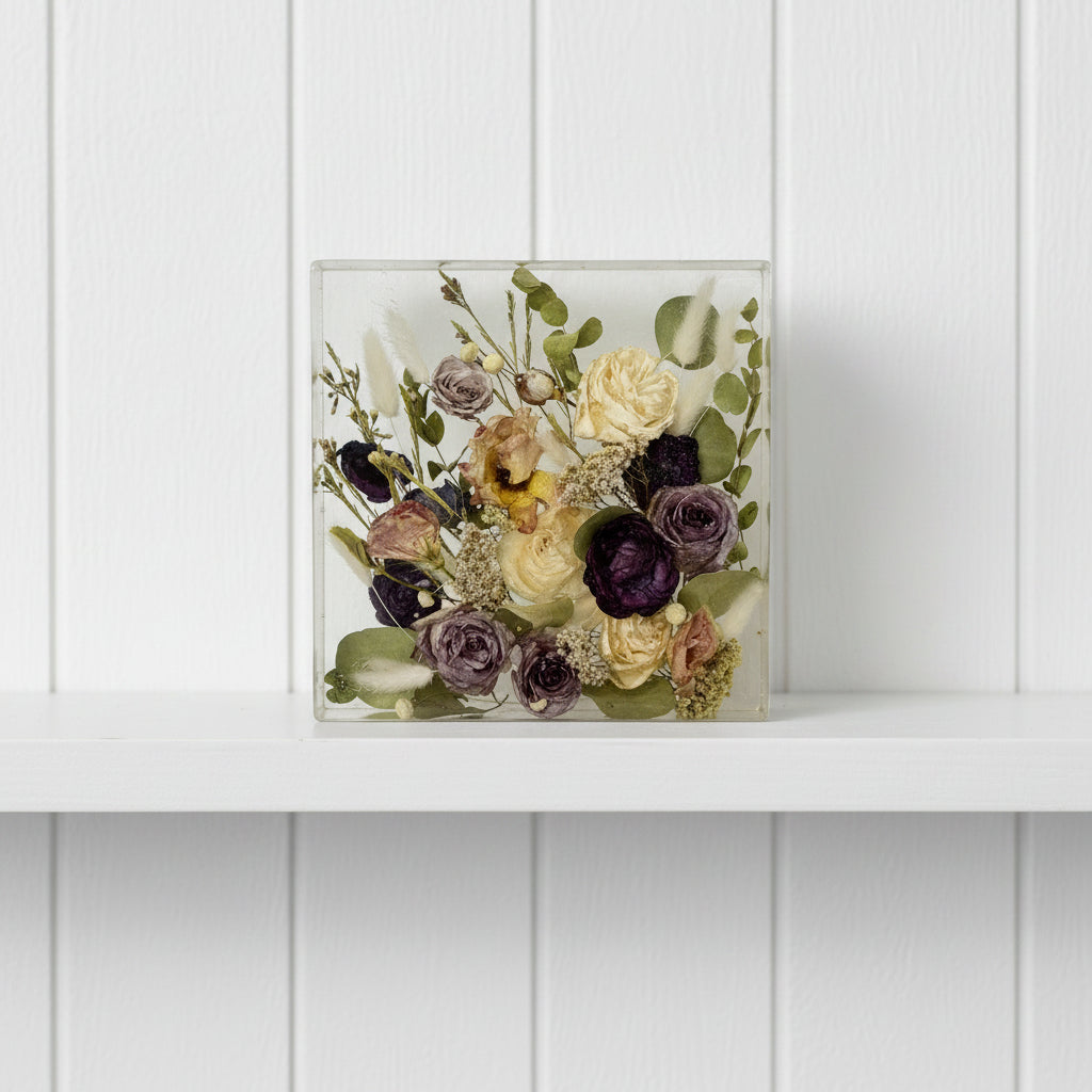 Pressed flowers in a clear rectangular block on a white background