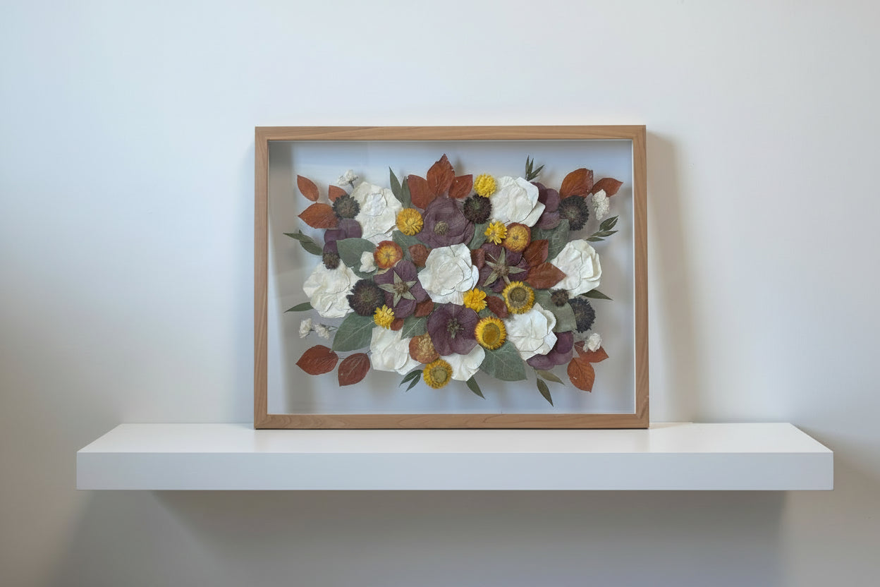 Framed arrangement of pressed flowers with a wooden frame on a white background