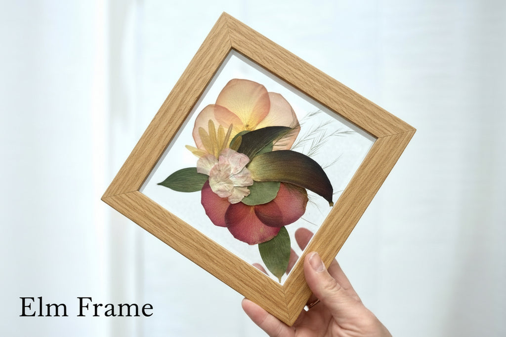 Hand holding a framed floral arrangement with 'Elm Frame' text on a white background