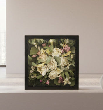 Framed floral arrangement on a white surface with a neutral background