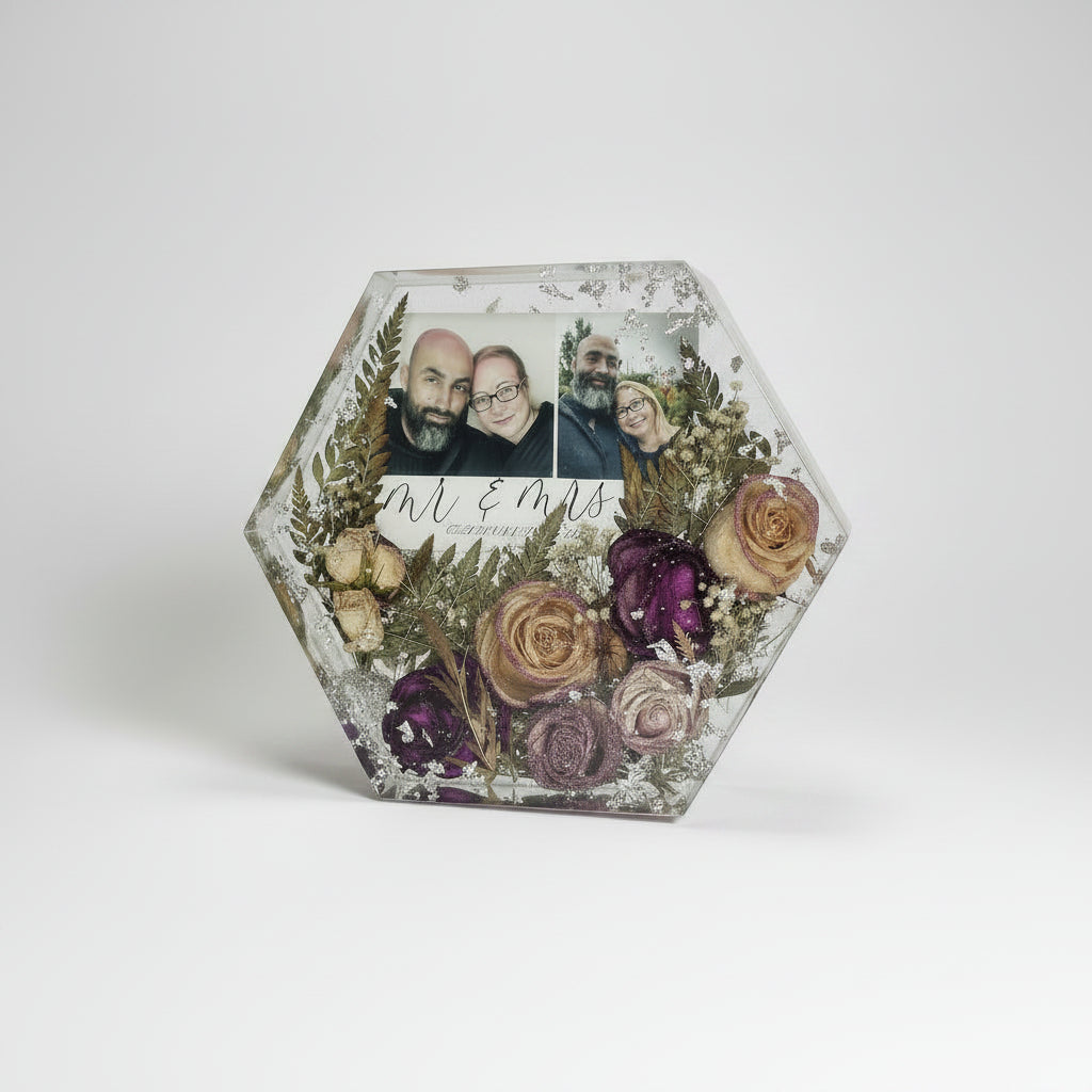 Hexagonal decorative box with dried flowers and family photos on a textured surface