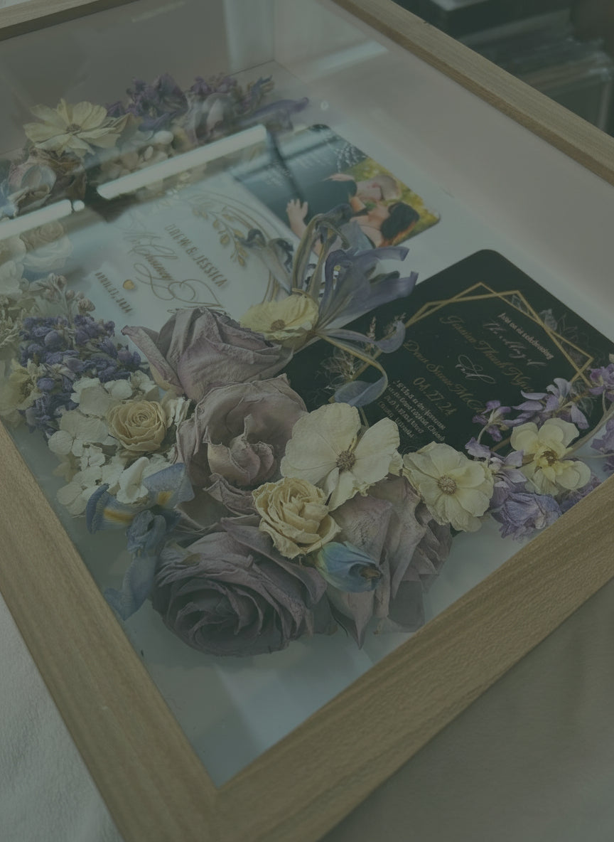Decorative display case with flowers and cards on a wooden surface