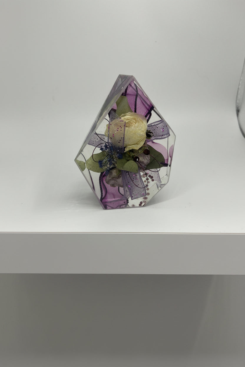 Gemstone resin shape with a white flower corsage with purple ribbon inside
