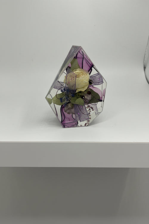 Gemstone resin shape with a white flower corsage with purple ribbon inside
