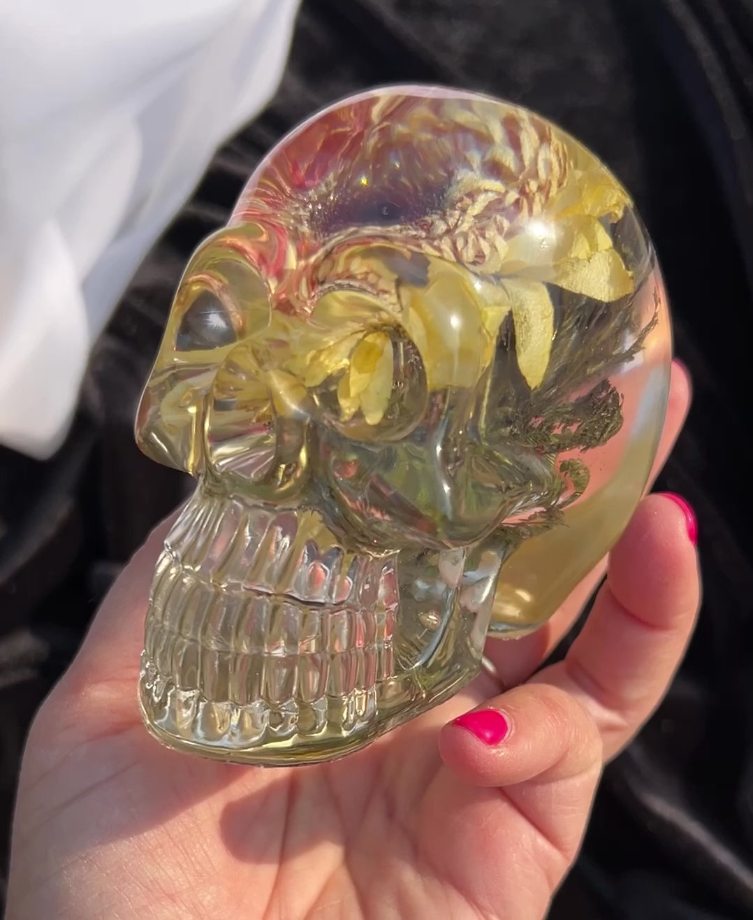 hand holding a clear skull with a yellow gerbera inside