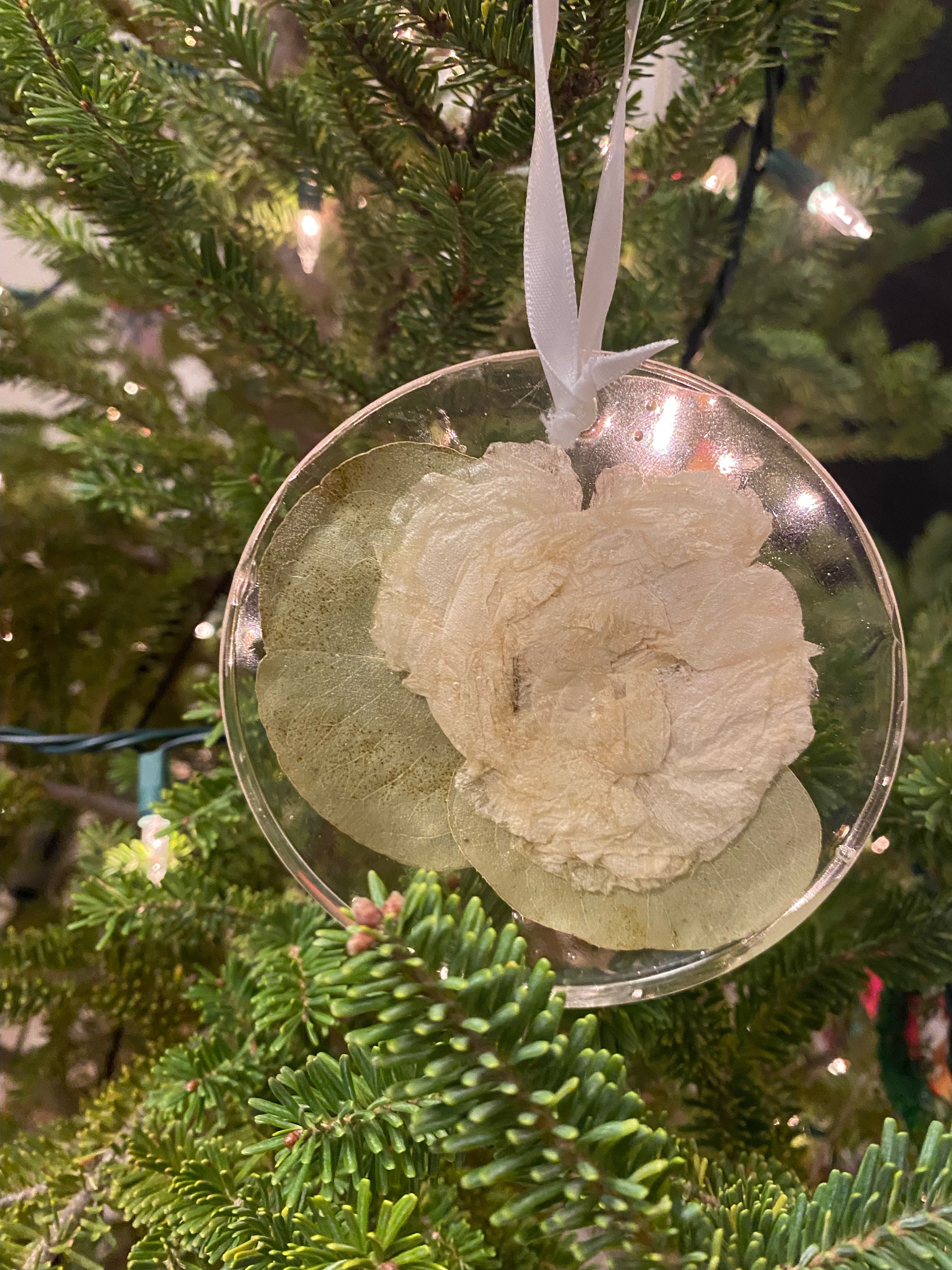 Decorative ornament with a white flower on a green Christmas tree