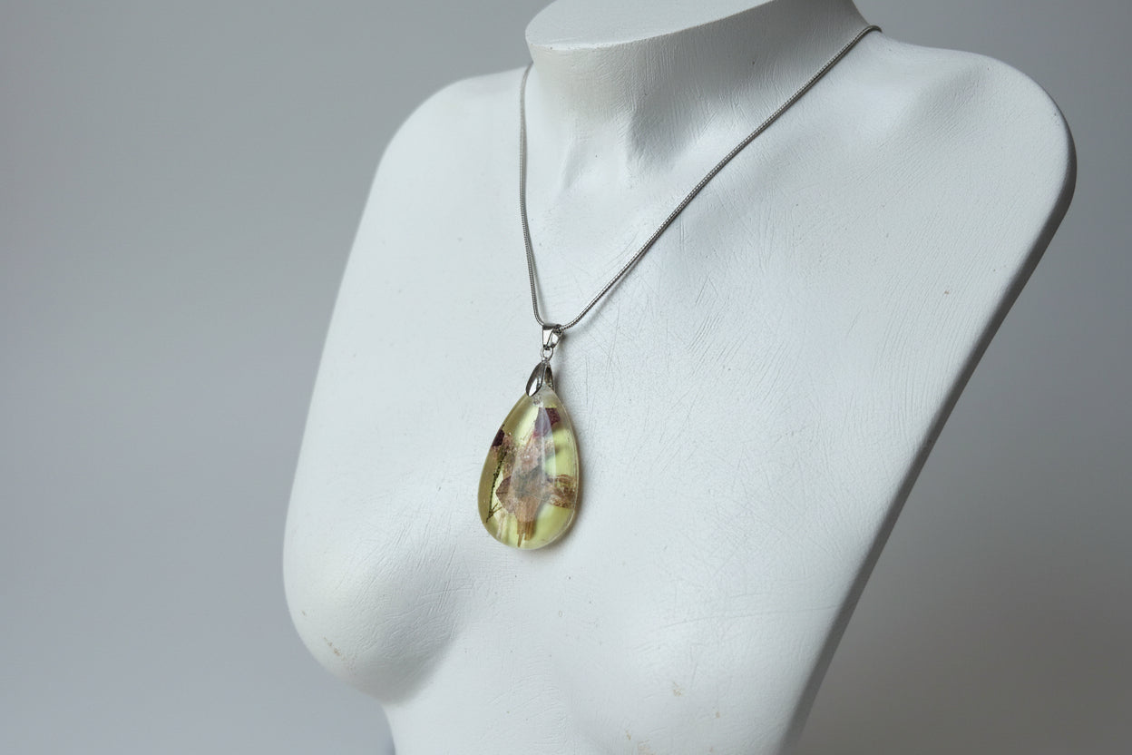 Teardrop-shaped pendant on a mannequin bust against a gray background